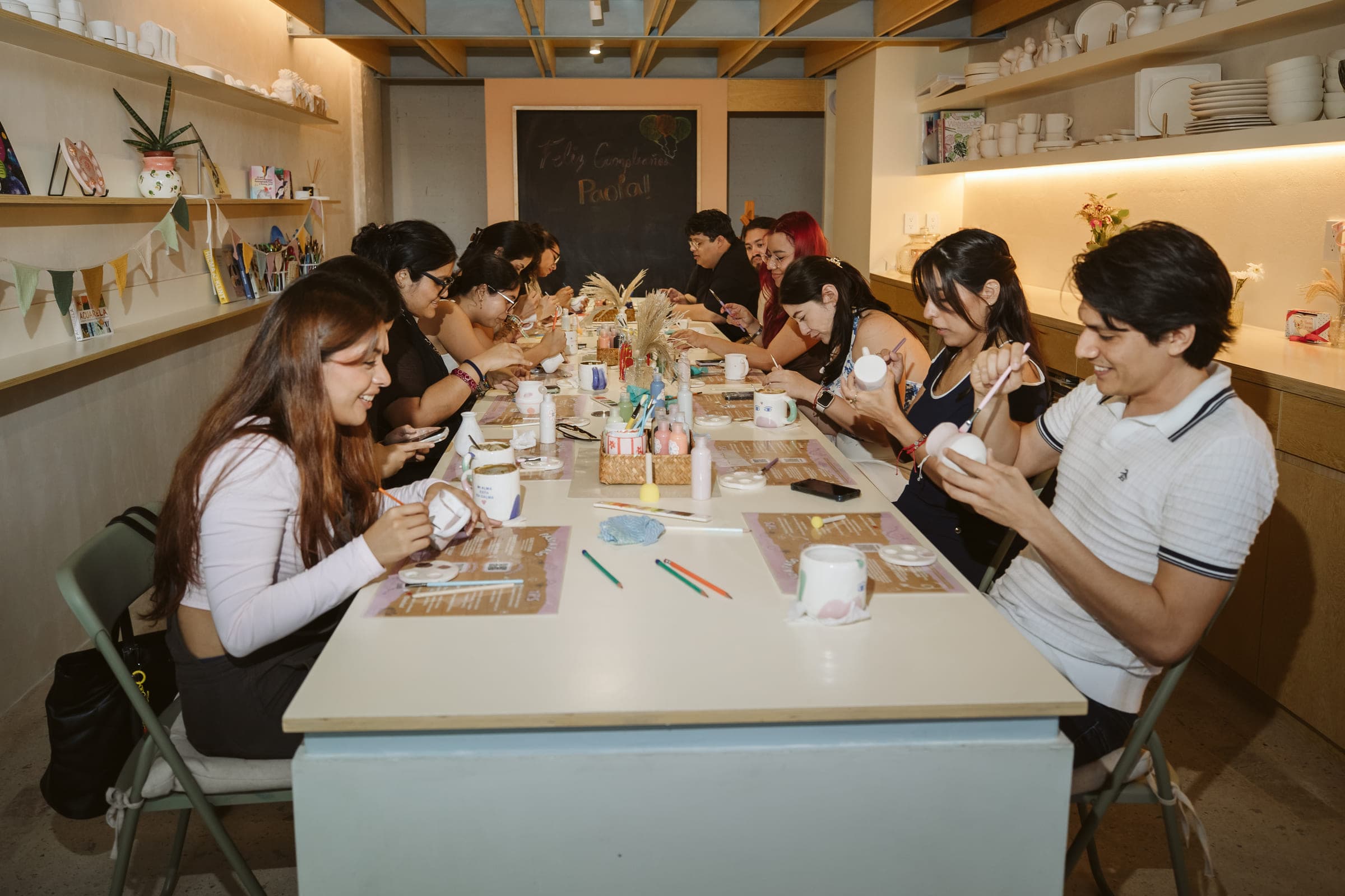 Mesa larga de La Ceramikería con varias personas pintando sus piezas de cerámica